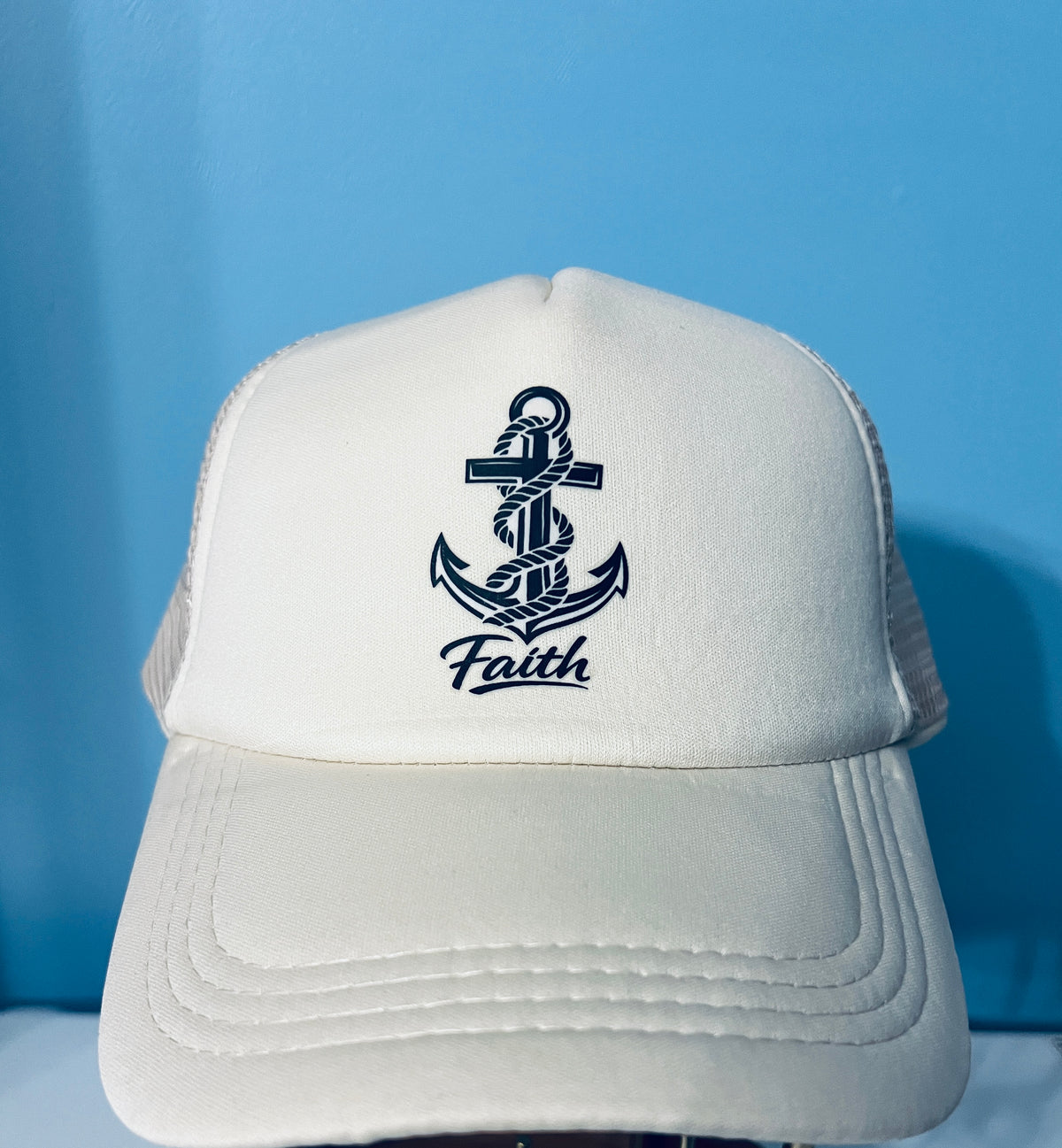 White cap with an anchor design and 'Faith' text on a blue background
