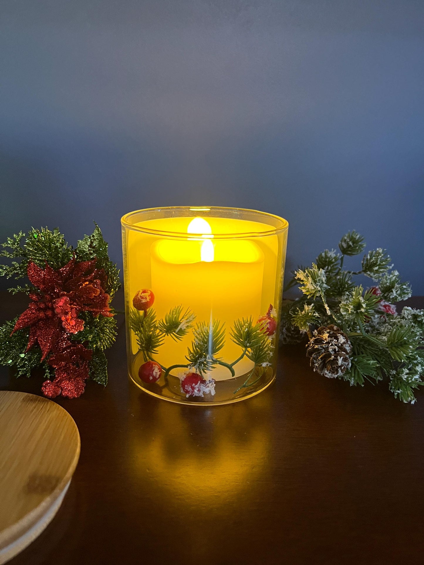 Candle in a clear glass jar with decorative elements on a dark surface with a blue background
