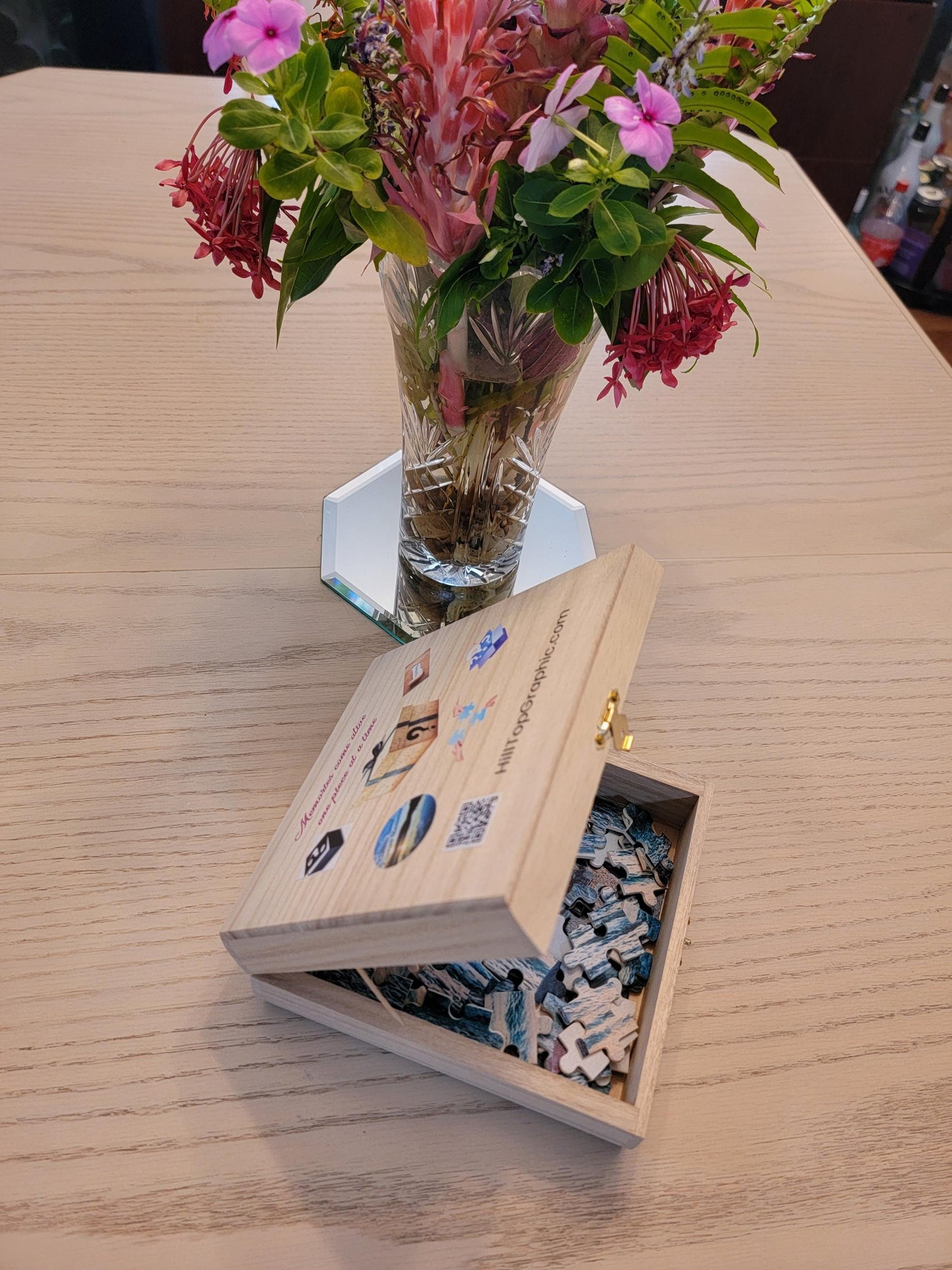 Wooden box with puzzle pieces on a table with flowers in the background