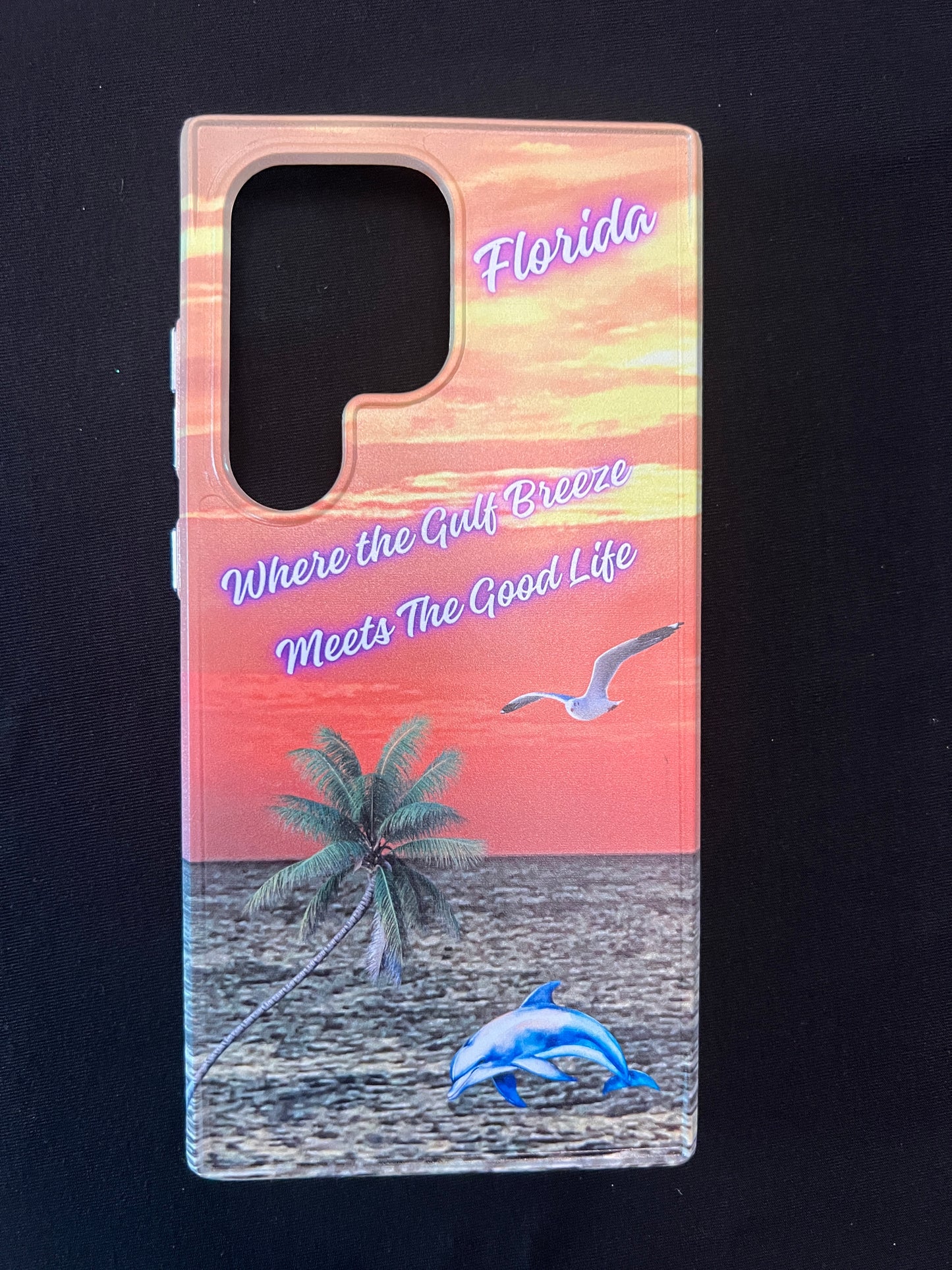 Phone case with Florida design featuring palm tree, dolphin jumping out of the water, seagull jumping out of the gulf water, beautiful Florida sunset, and text with the phrase "where the gulf breeze meets the good like" Florida