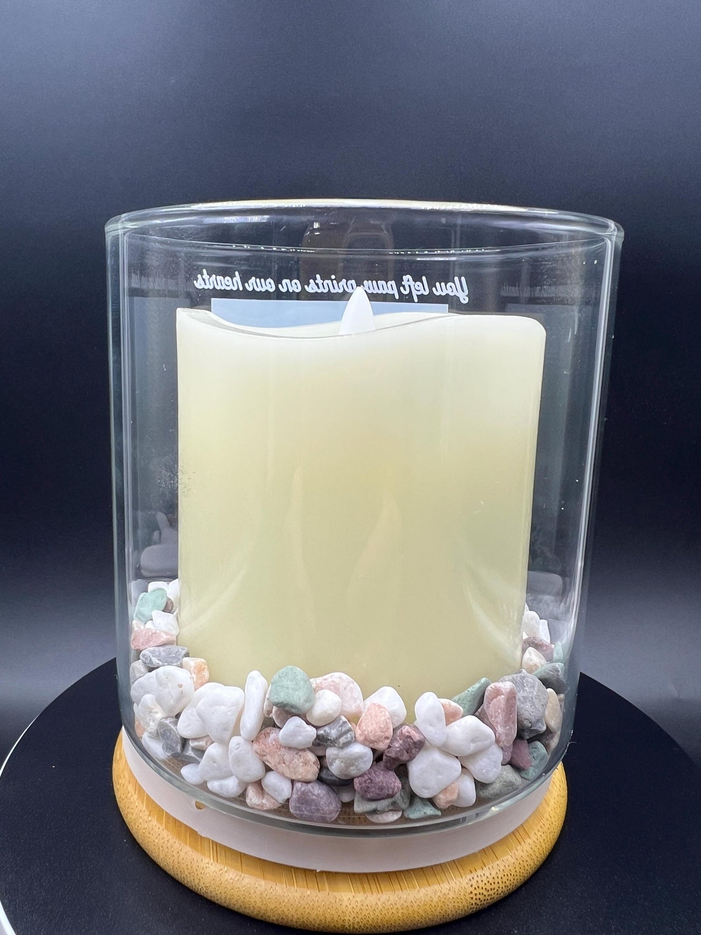 Candle in a glass container with river rock showing at the bottom of the glass jar. 