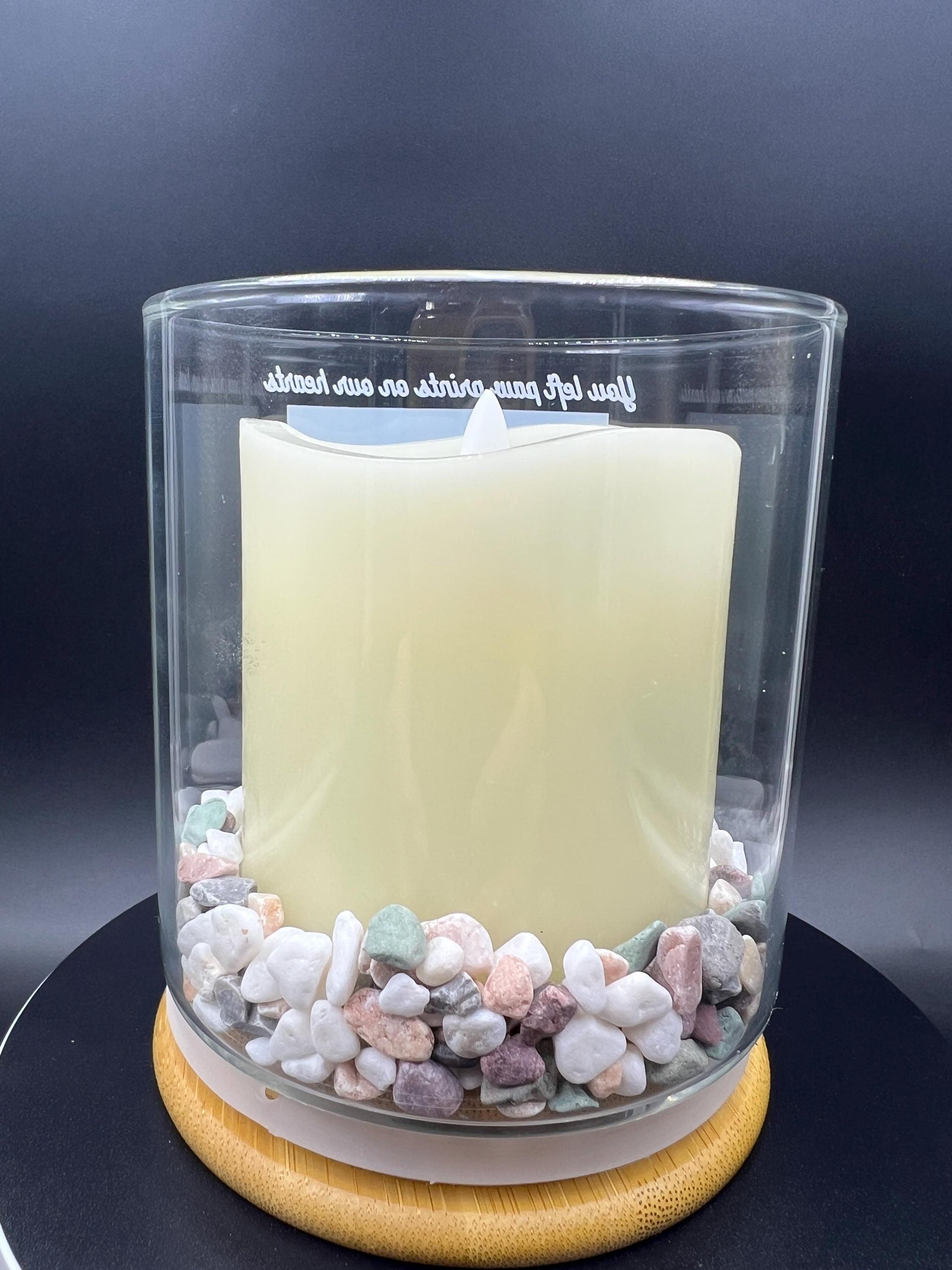 Candle in a glass container with river rock showing at the bottom of the glass jar. 