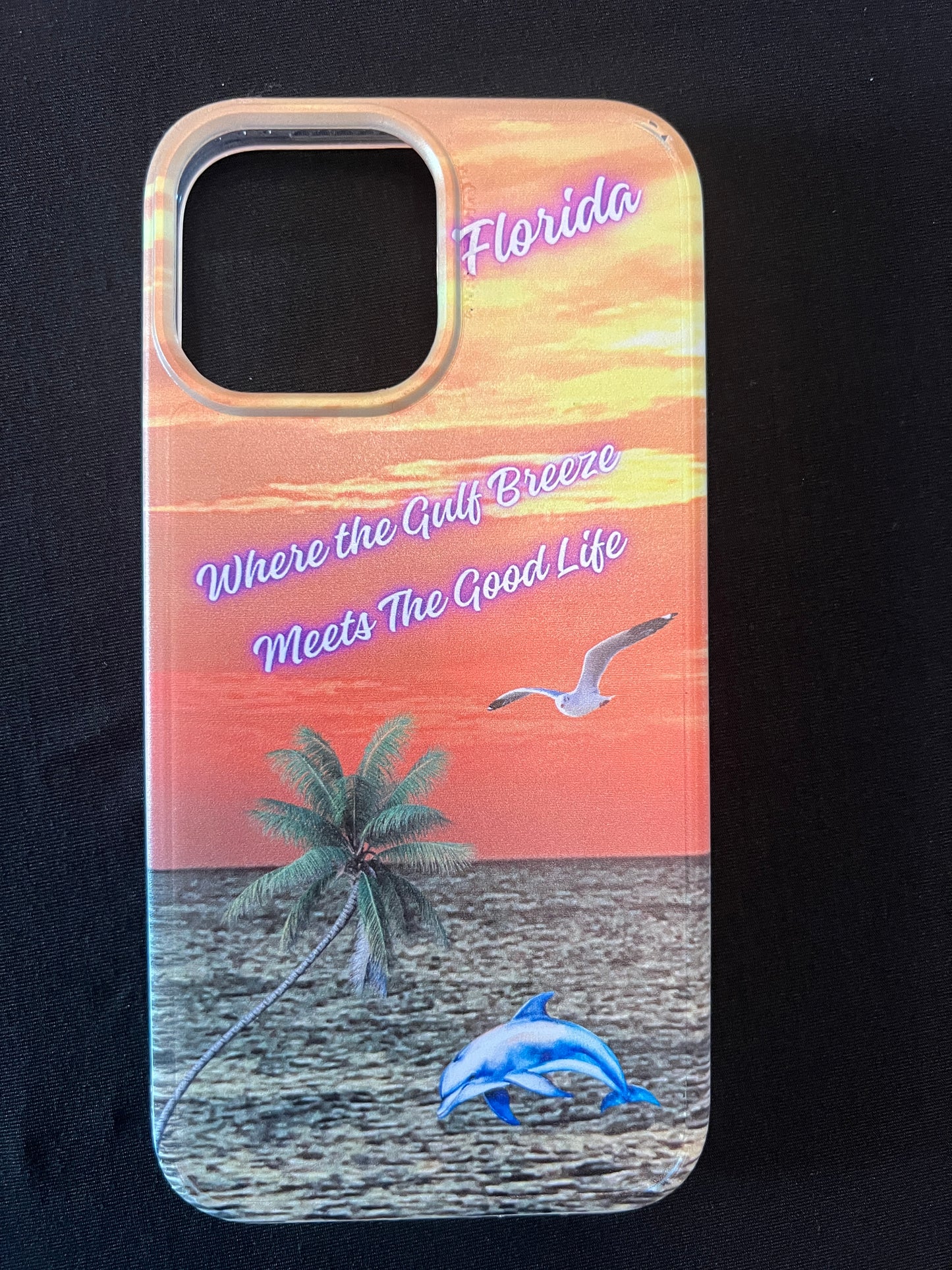 Phone case with Florida design featuring palm tree, dolphin jumping out of the water, seagull jumping out of the gulf water, beautiful Florida sunset, and text with the phrase "where the gulf breeze meets the good like" Florida