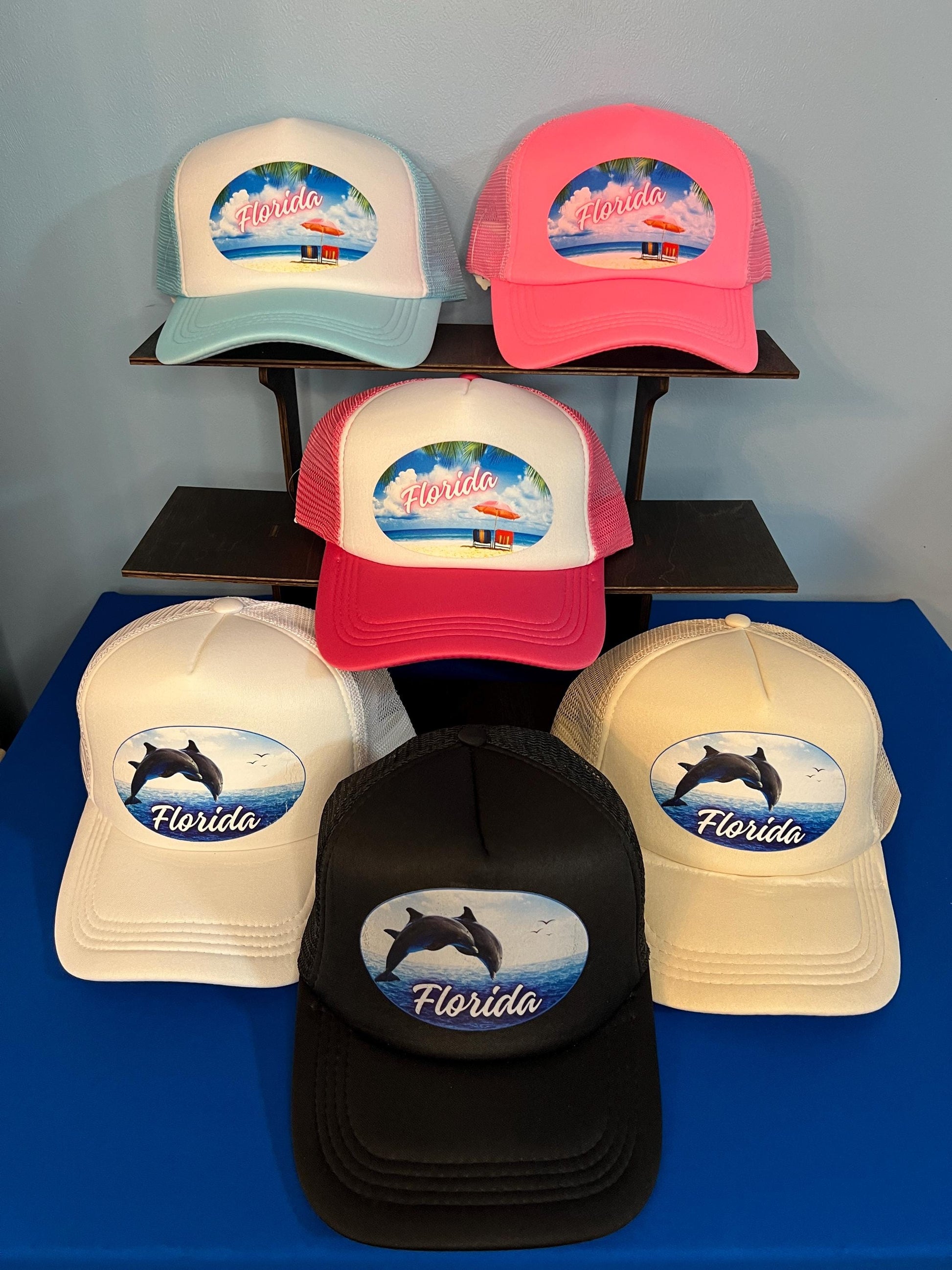 Collection of Florida-themed hats on a display stand with a blue background
