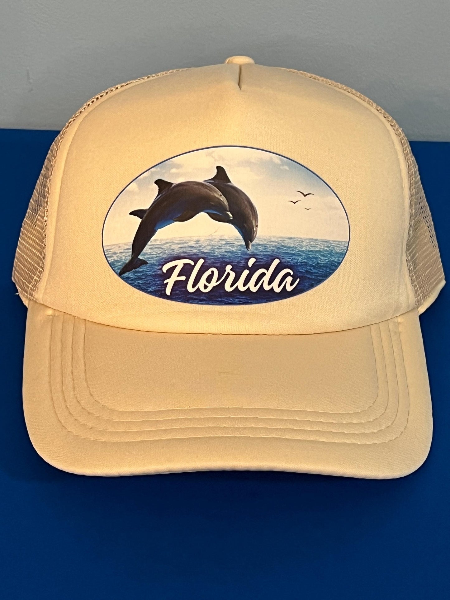 Beige trucker hat with dolphin design and 'Florida' text on a blue background