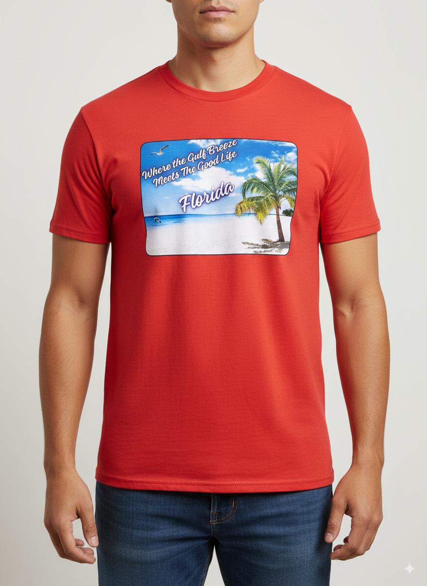 Person wearing a orange  'Florida' t-shirt on a beach with a sailboat and palm trees in the background. T-shirt has a  picture on the front of white sand beach, aqua gulf waters, palm tree and the text "where the gulf breeze meets the good life" Florida. 